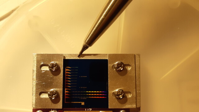 Array of phononic tunnel junctions of varying length on a silicon chip. Rainbow colors come from the sub-micron mesh in the silicon nitride waveguides.