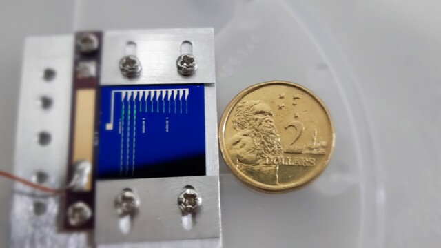 Phononic chip with an australian two dollar coin for scale.