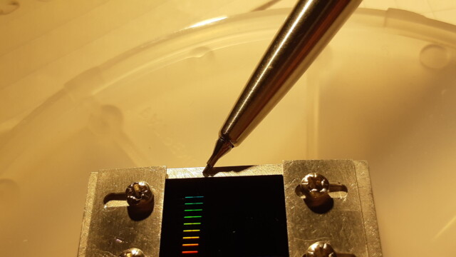 Array of phononic tunnel junctions of varying length on a silicon chip. Rainbow colors come from the sub-micron mesh in the silicon nitride waveguides.